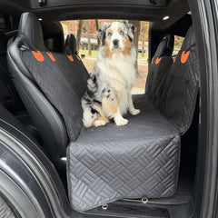 A car back seat extender for dogs with an Australian Shepherd sitting on the spacious quilted cover