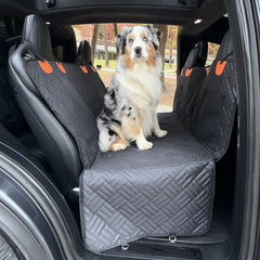 A car back seat extender for dogs with an Australian Shepherd sitting on the spacious quilted cover