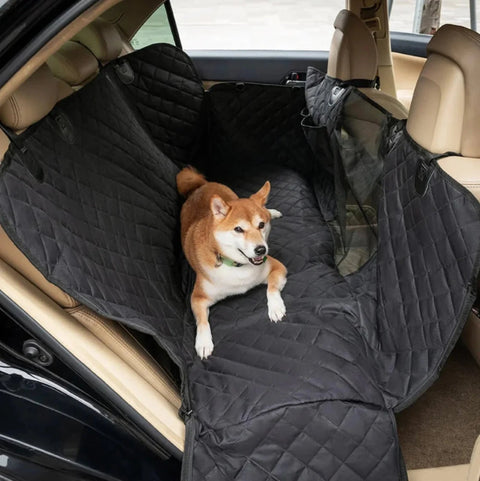 Shiba lies on quilted black car hammock in back seat