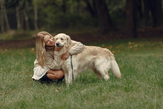Woman hugging a Golden Retriever in a grassy park