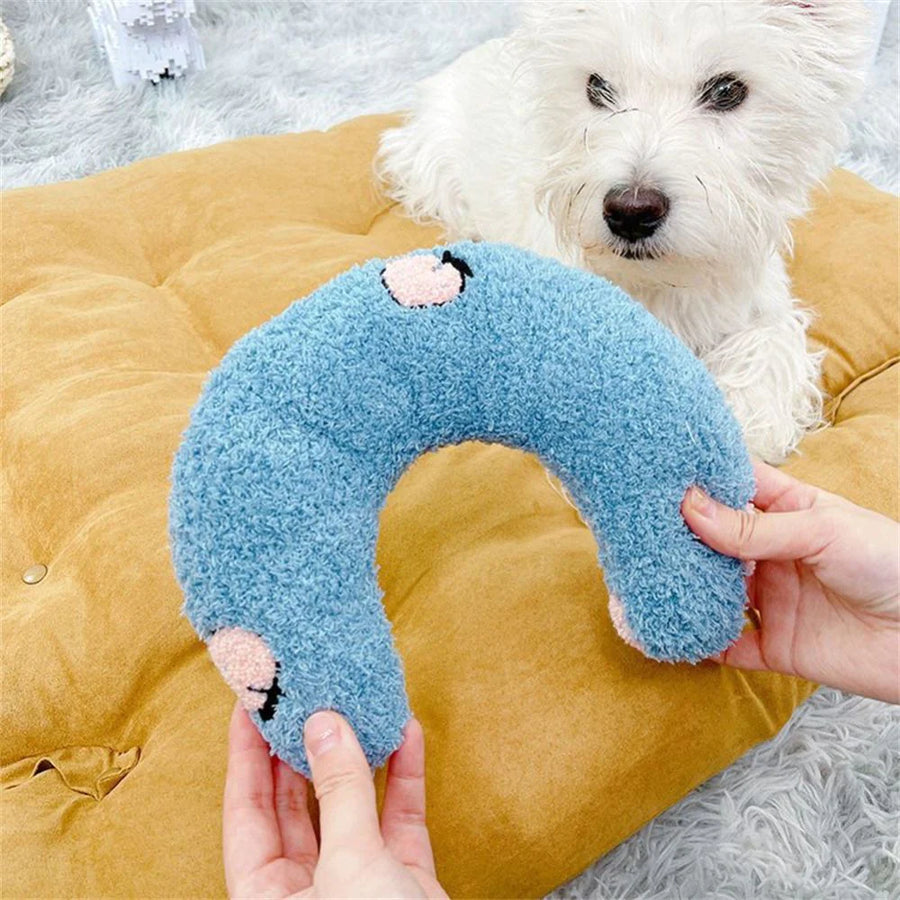 hands hold a blue u shaped cushion on a soft bed as a calming pillow for dogs