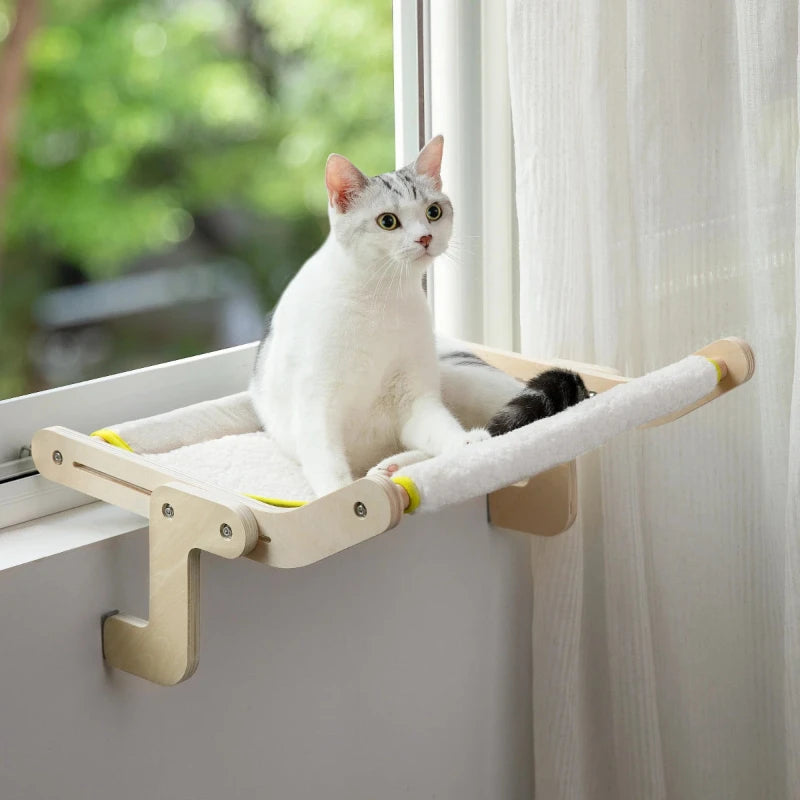 Cat resting on a window-mounted hammock perch, enjoying a comfortable elevated view in a cozy indoor space.