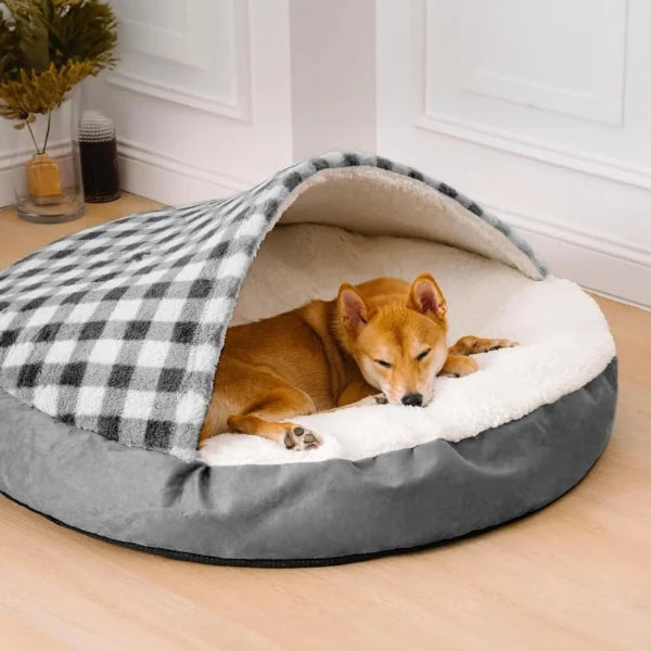 Dog resting in a cozy covered bed with soft plush lining and checkered hood, offering warmth and comfort for pets.