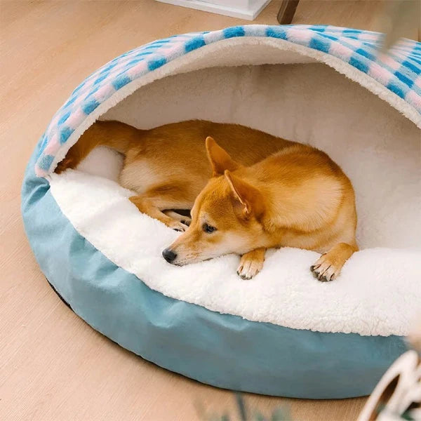 Dog resting in cozy covered bed with blue and pink plaid design, offering plush comfort and warmth for ultimate relaxation.