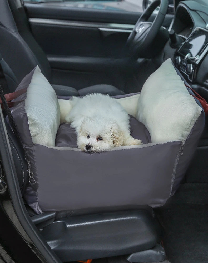 Small white dog lying in a dog car seat bag on the passenger seat
