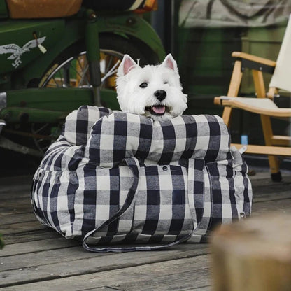 West Highland White Terrier enjoying a cozy black and white checkered dog car seat with seatbelt, ideal for travel comfort.