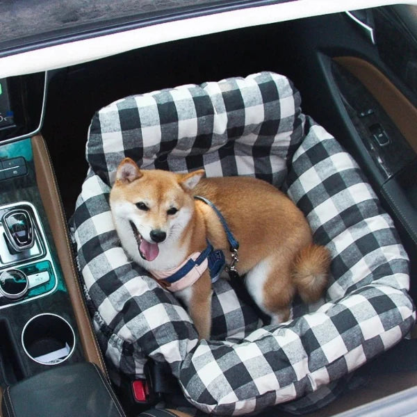 Shiba Inu relaxing in a black and white checkered dog car seat with seatbelt, perfect for safe and cozy travel.