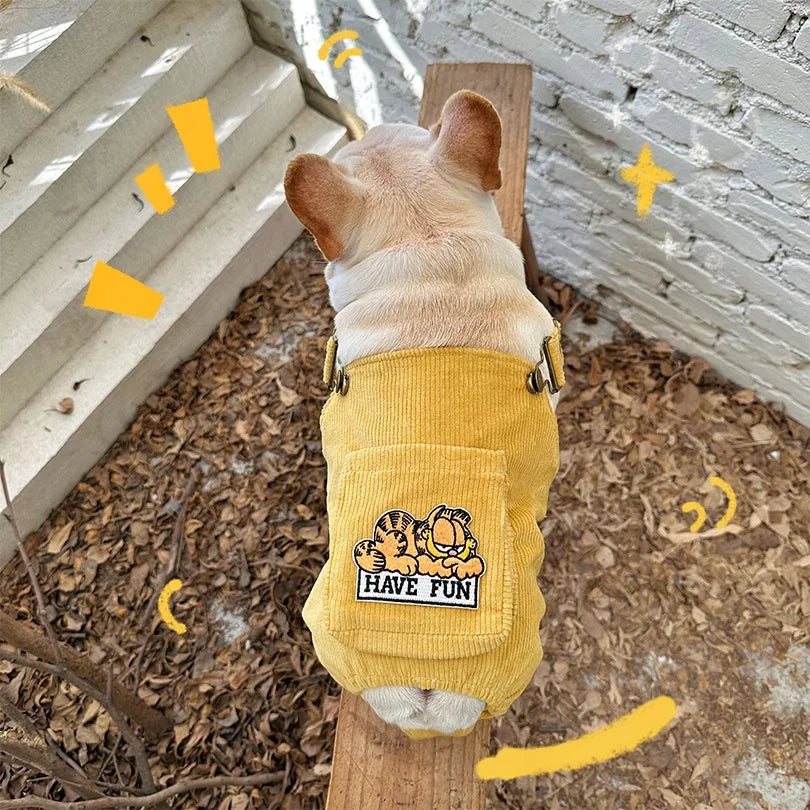 French bulldog outdoors in a yellow farmer dog outfit with shoulder straps and a back pocket