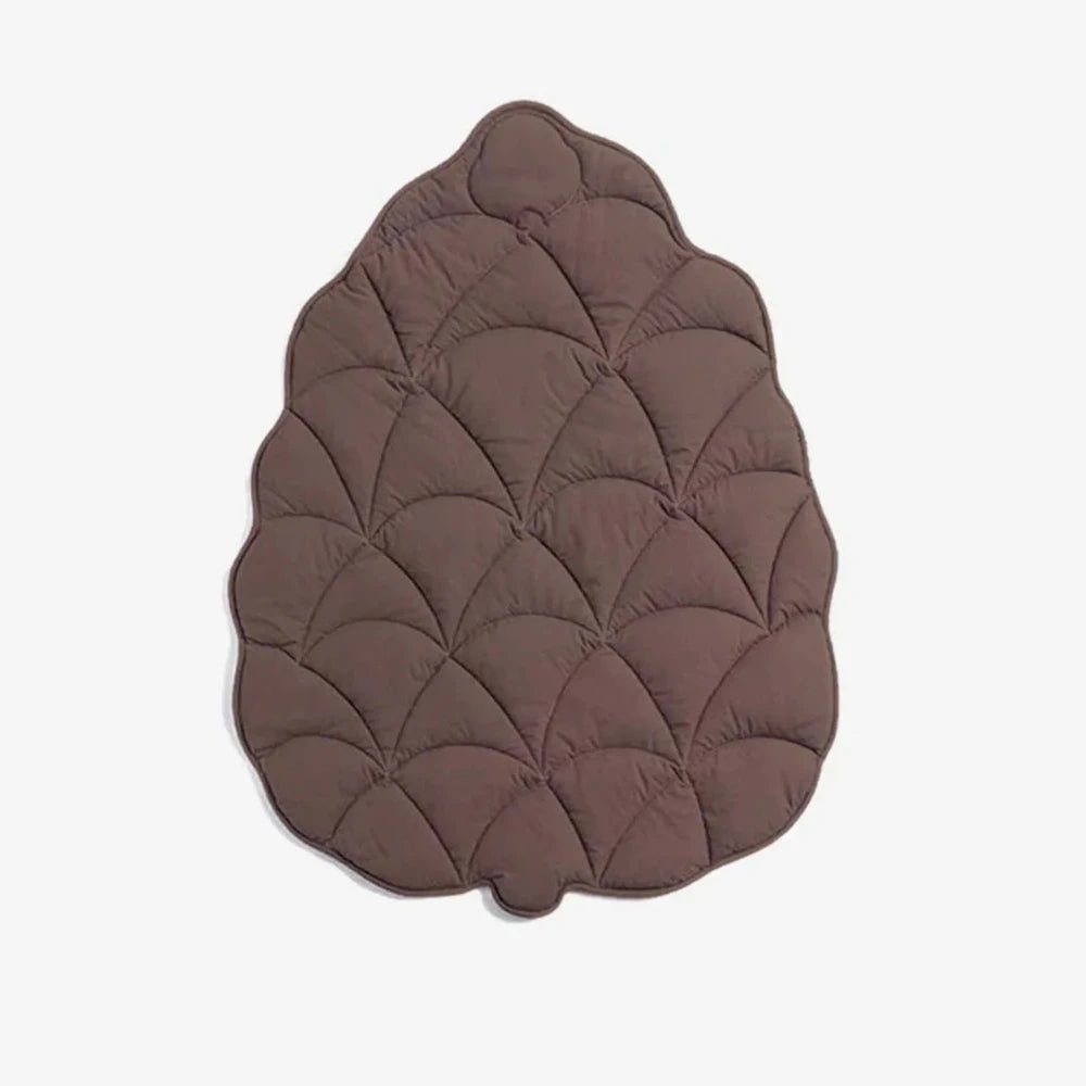 Brown dog floor mat in leaf shape with quilted stitching on a white background