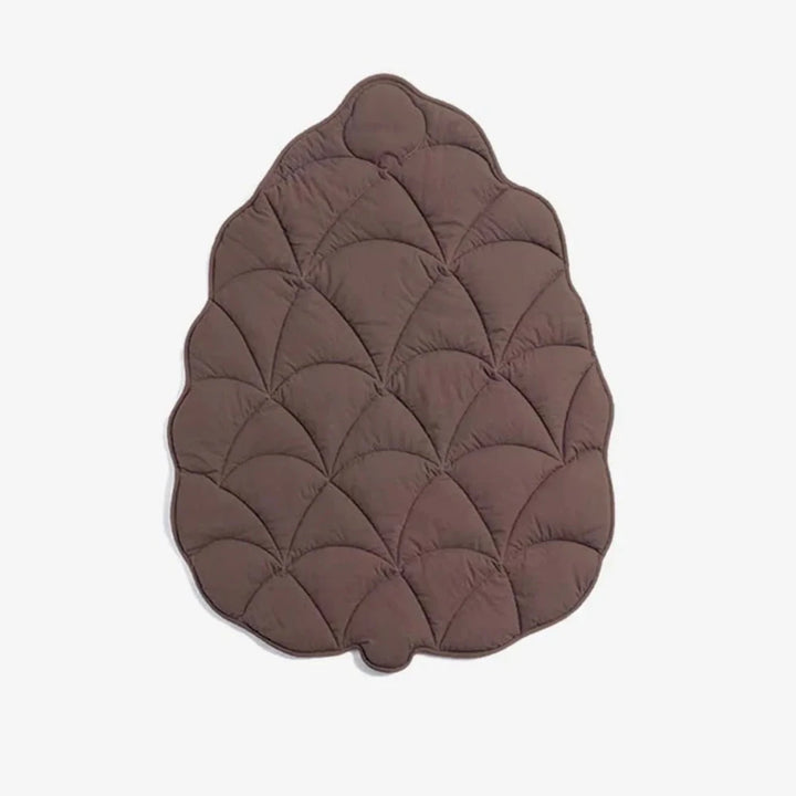 Brown dog floor mat in leaf shape with quilted stitching on a white background