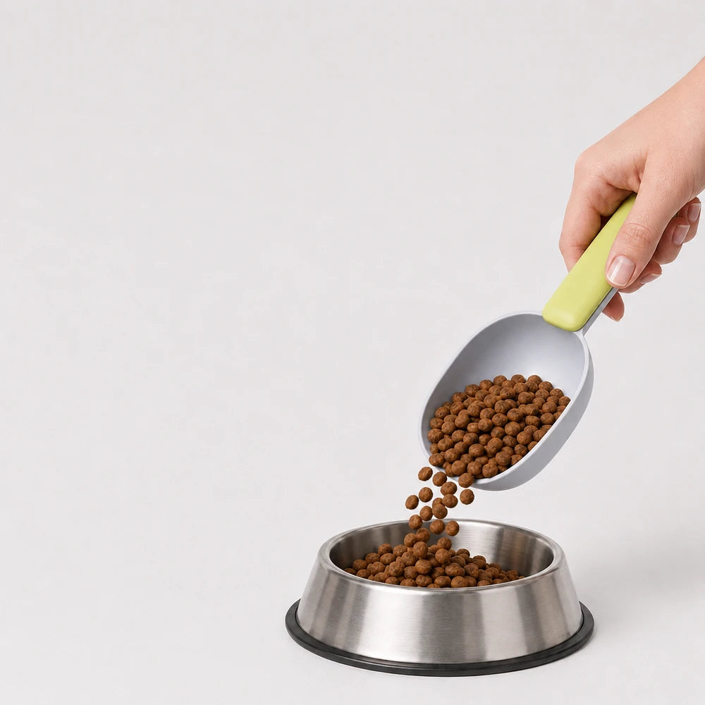 Pet food scooper pouring dry dog food into a stainless steel bowl