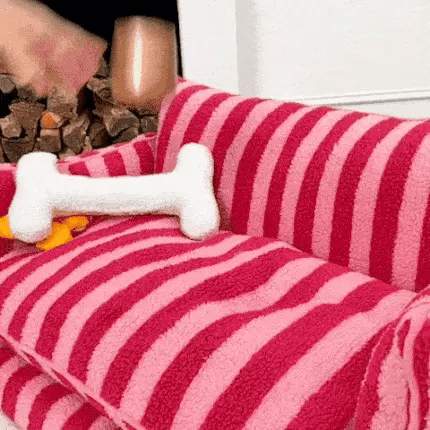 hand pressing the seat of a large sofa dog bed with pink striped plush fabric in a cosy room