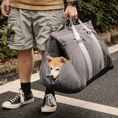 Man carrying gray portable seat with dog inside on the street