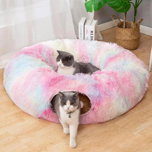 Two grey cats in a fluffy, pastel-colored cat bed with a tunnel, one exiting through the opening.