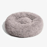 Fluffy round dog bed in light brown on a clean white background