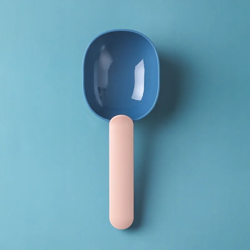 Pink and blue pet food scoop shown on a teal background