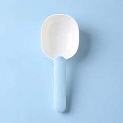 Blue and white pet food scoop shown on a blue background
