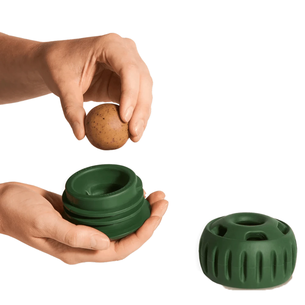 Hands demonstrating how to insert a treat into a freezable dog toy, highlighting its treat-dispensing design and functionality.