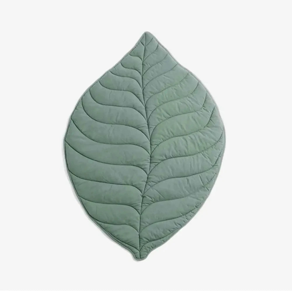 Green dog floor mat in leaf shape with quilted stitching on a white background