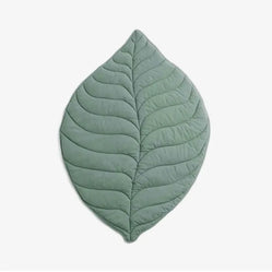 Green dog floor mat in leaf shape with quilted stitching on a white background