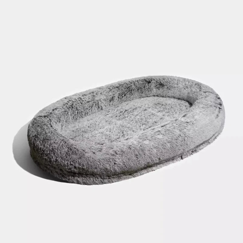 Soft and fluffy gray dog bed with an oval shape, perfect for providing comfort and warmth to pets.