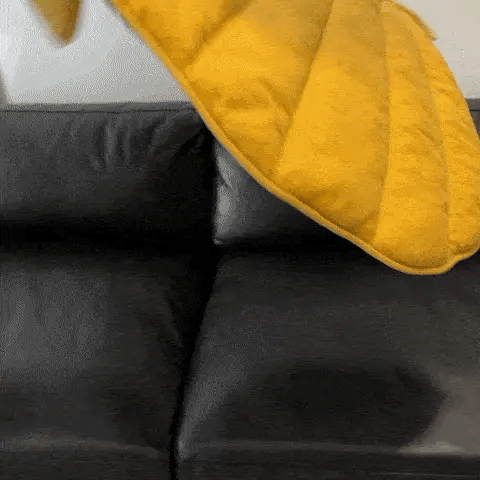 Soft and cozy leaf-shaped pet mat being placed on a couch, perfect for protecting furniture while offering pet comfort.