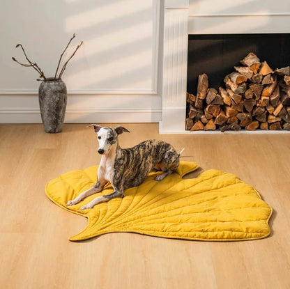 Stylish yellow leaf-shaped pet mat with a Whippet dog lounging in a cozy living room by the fireplace.