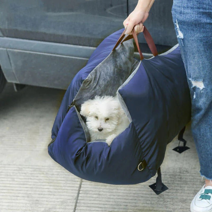 Small white puppy carried safely in a soft blue travel bag.