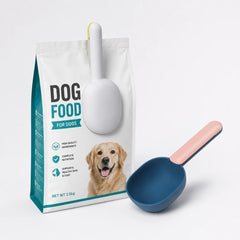 Pet food scoop and clip attached to a bag of dog food beside a blue scoop