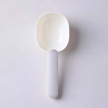 Minimalistic white pet food scoop with ergonomic handle, ideal for scooping pet food. Lightweight and easy to clean.