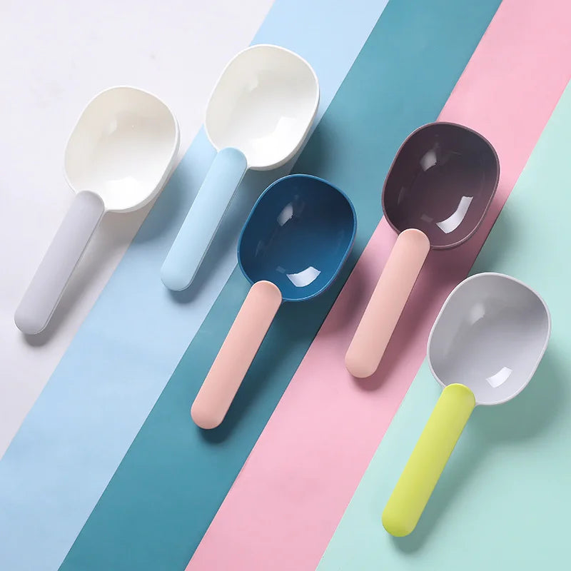 Plastic pet food scoops in different colours arranged on a pastel background