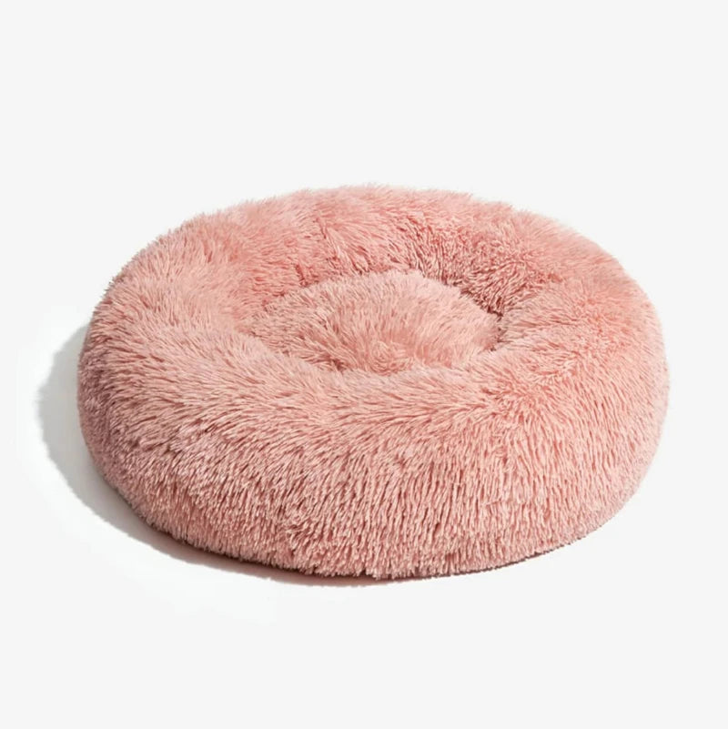 Pink plush round dog bed on a clean white background
