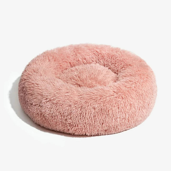 Pink plush round dog bed on a clean white background