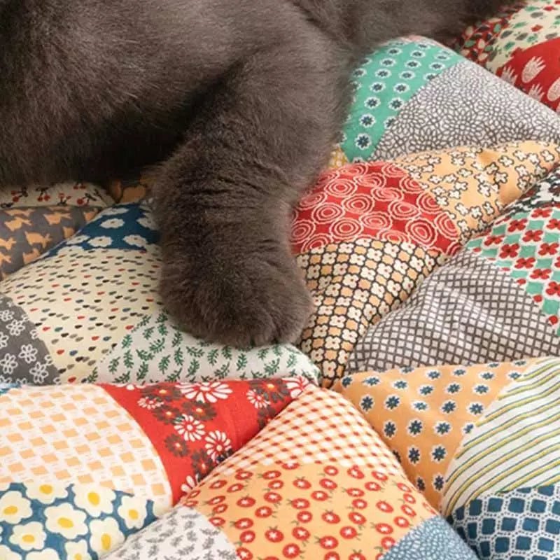 Close-up of a cat's paw resting on a vibrant rainbow patchwork sofa cover, offering comfort and style for pets.