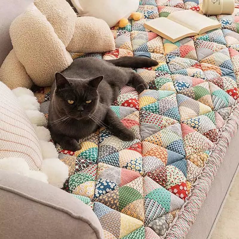 Cat lounging comfortably on a colorful rainbow patchwork sofa cover, perfect for protecting furniture with added style.