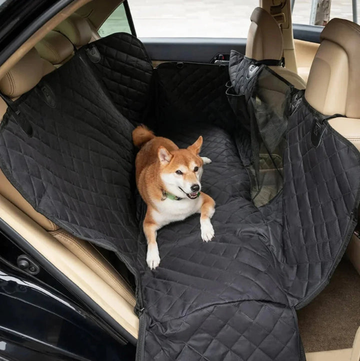 Shiba lies on quilted black car hammock in back seat