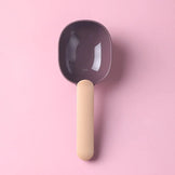 Pink and brown pet food scoop shown on a pink background