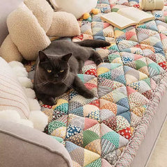 Black cat lounging on pet cover for sofa on couch