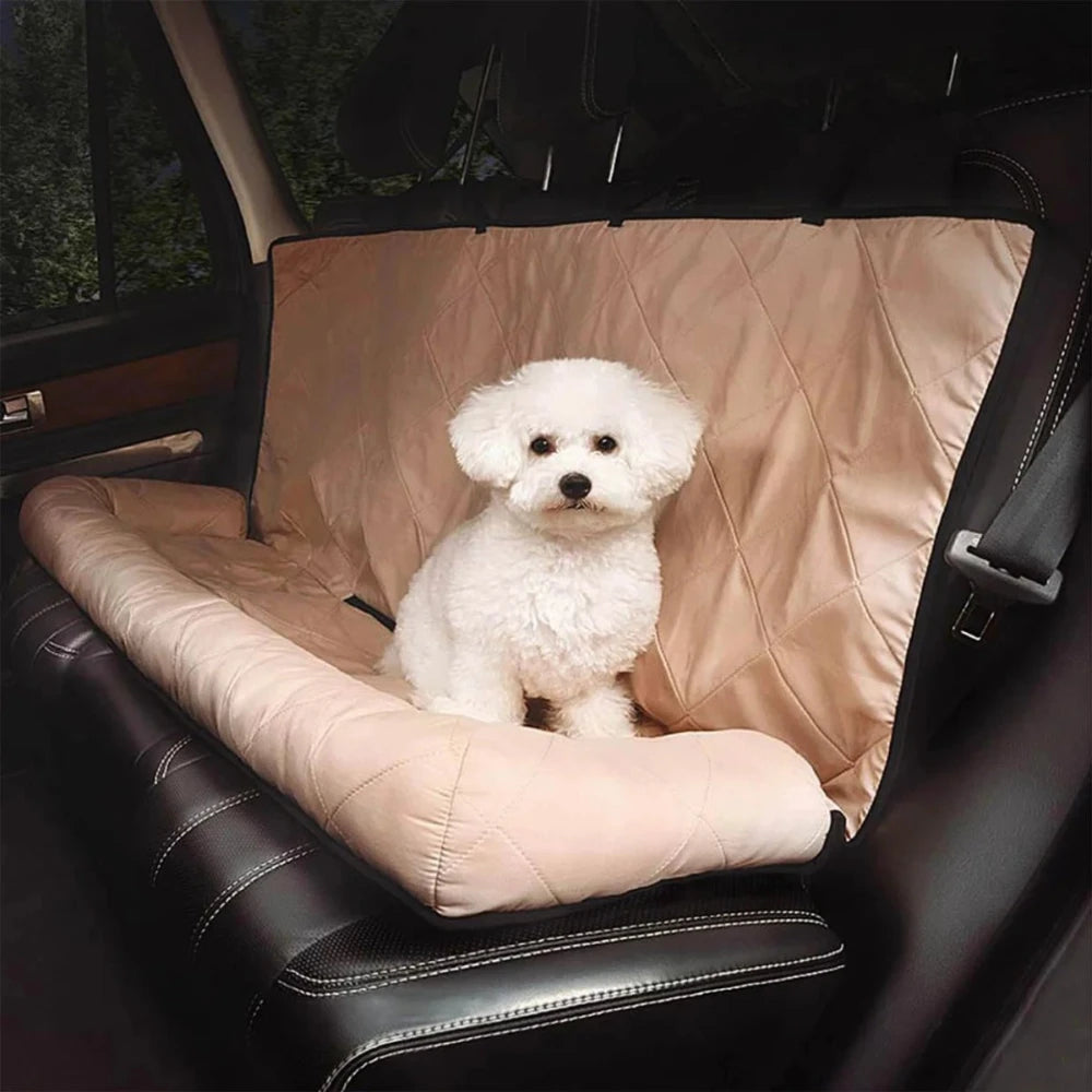 Small white dog sitting on a beige waterproof dog car seat cover with pillow, offering comfort and protection during travel.