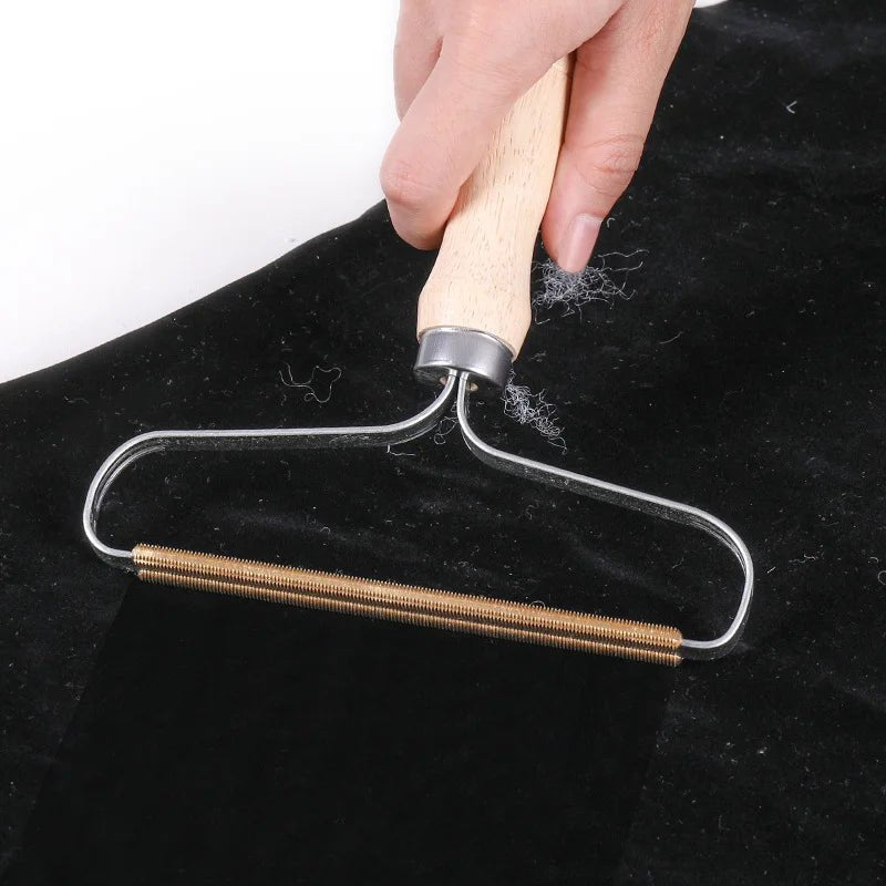 Efficient wooden pet fur remover tool with metal frame, removing pet hair from black fabric, ideal for easy cleaning.