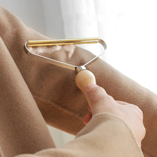 Wooden pet fur remover tool gently removing hair from a beige coat, perfect for fabric cleaning and pet owners.